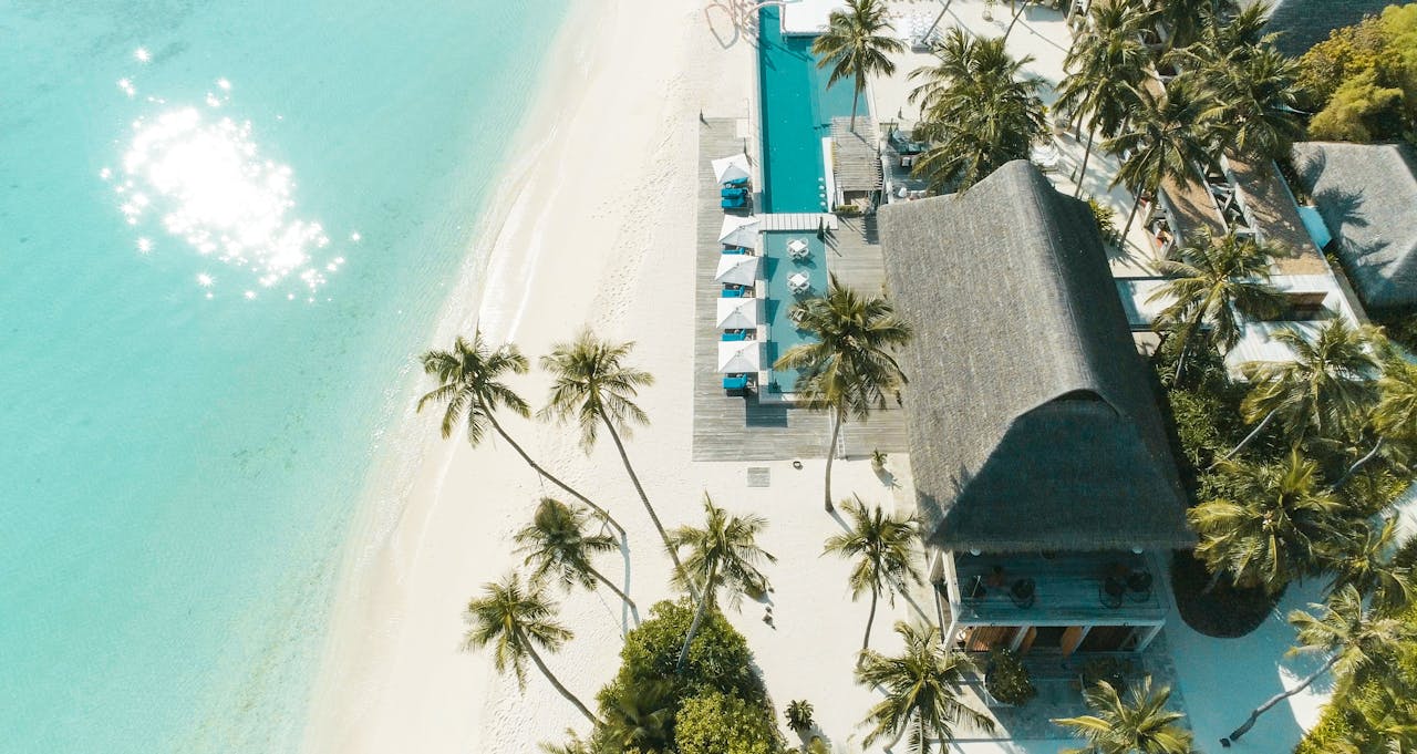 our-services-1 A stunning aerial view of a tropical beach resort with palm trees, turquoise waters, and white sand.