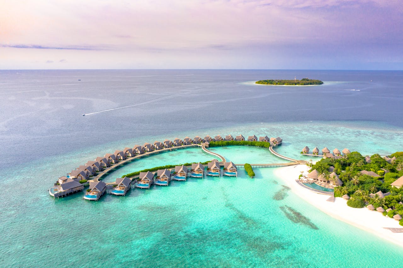 our-services-3 Idyllic aerial view of luxury overwater villas on a tropical island's crystal-clear waters.