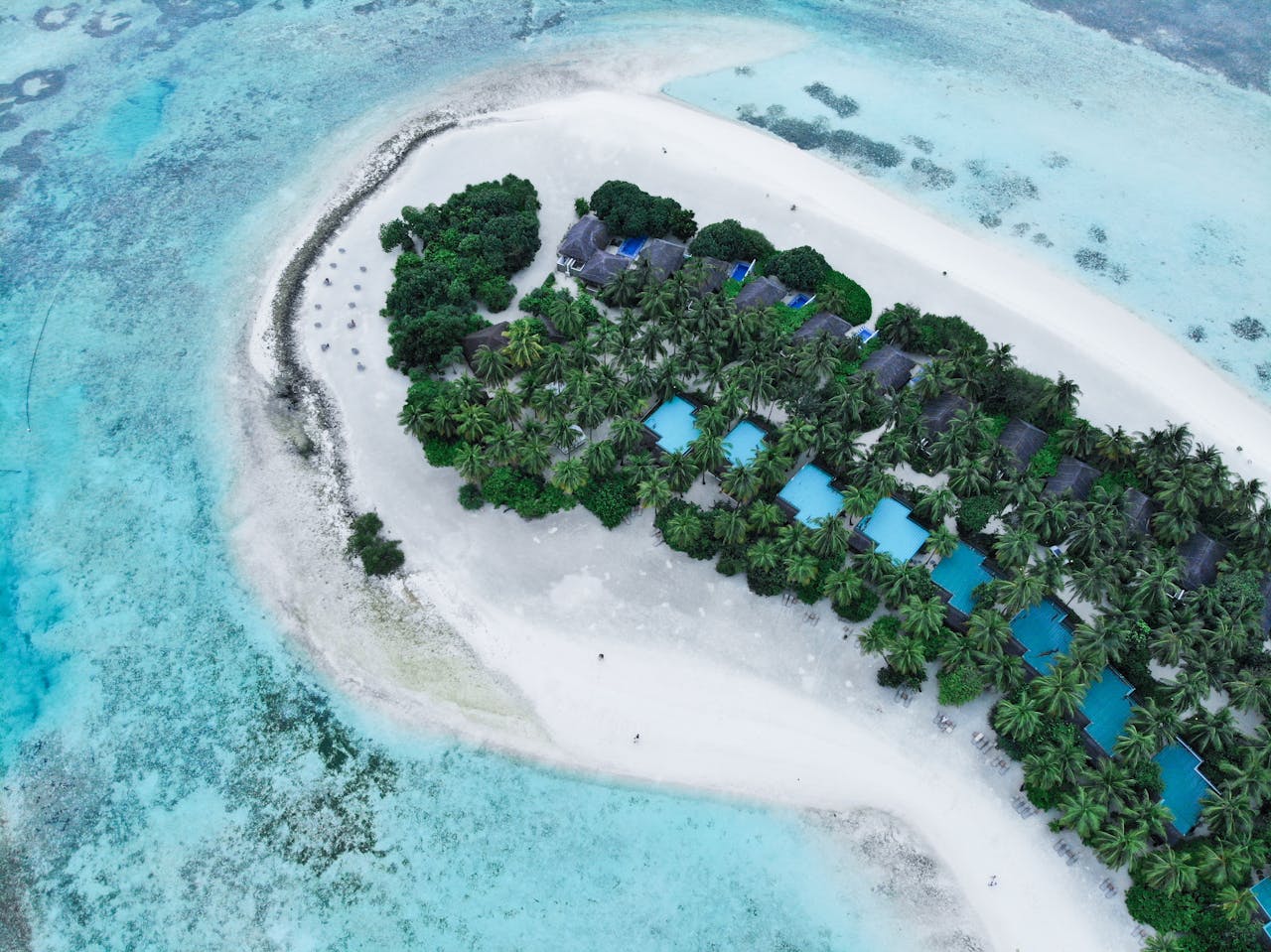 A stunning aerial view of a tropical island resort with turquoise waters and lush greenery.