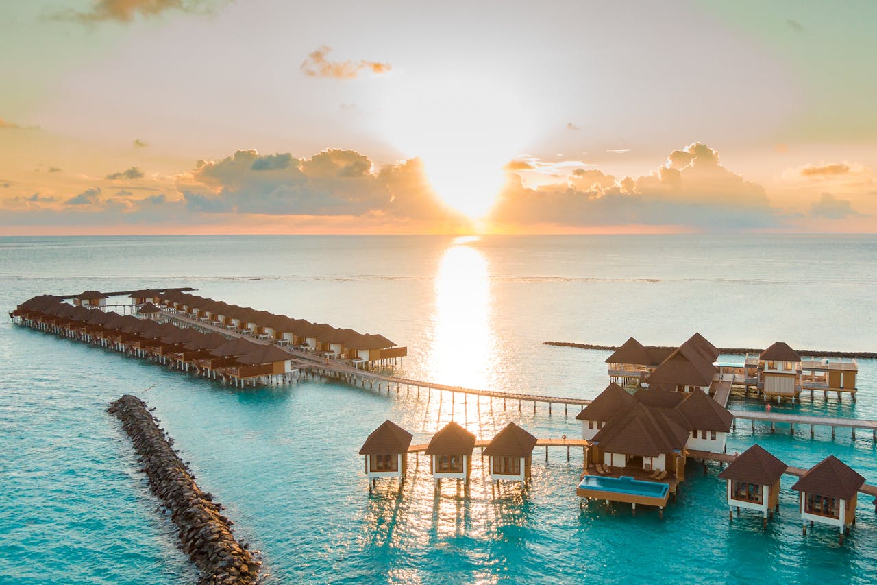 gallery-1 Captivating aerial view of luxurious Maldives overwater villas at sunrise, perfect for a serene vacation.